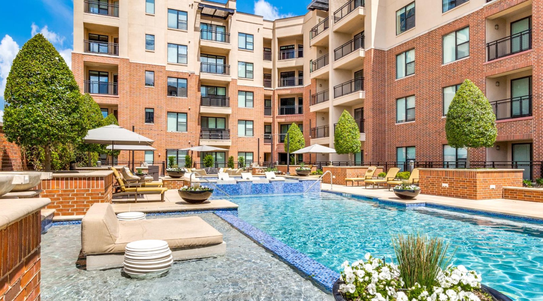 Resort-style swimming pool a pool with chairs and tables by it and buildings around it