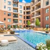 a pool with chairs and tables by it and buildings around it