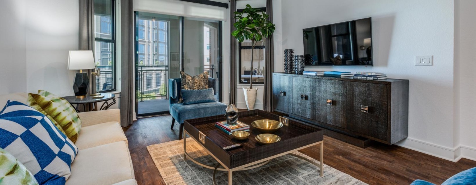 Living room with sliding glass door that leads to the patio at The Armstrong at Knox apartments for rent in Dallas, TX.